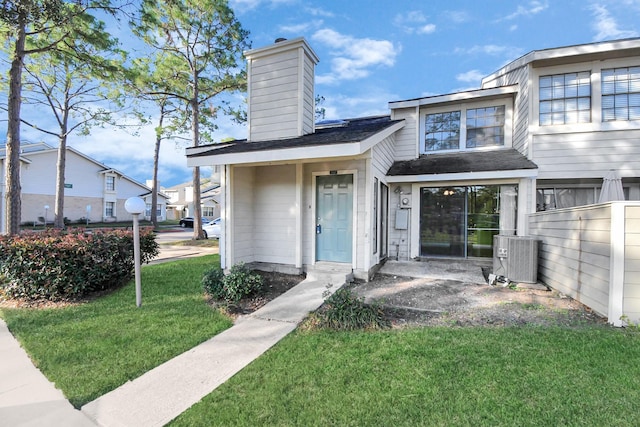 view of exterior entry featuring a yard and central AC unit