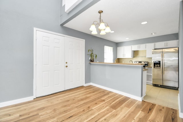 kitchen featuring white cabinets, stainless steel refrigerator with ice dispenser, hanging light fixtures, kitchen peninsula, and a chandelier