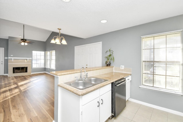 kitchen featuring white cabinets, vaulted ceiling, sink, decorative light fixtures, and dishwasher