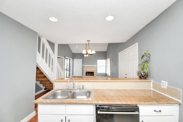 kitchen with an inviting chandelier, sink, hanging light fixtures, a textured ceiling, and black dishwasher