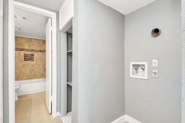 clothes washing area with light tile patterned floors, washer hookup, a textured ceiling, and hookup for an electric dryer