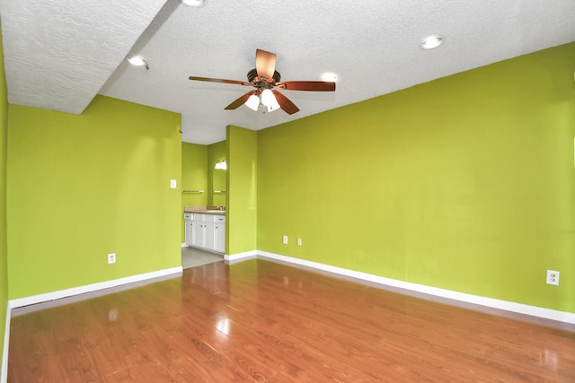 unfurnished room featuring ceiling fan, hardwood / wood-style floors, and a textured ceiling