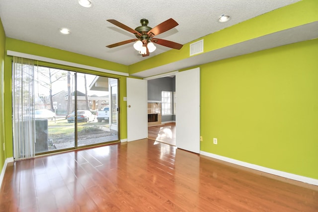 empty room featuring hardwood / wood-style floors, ceiling fan, and a textured ceiling