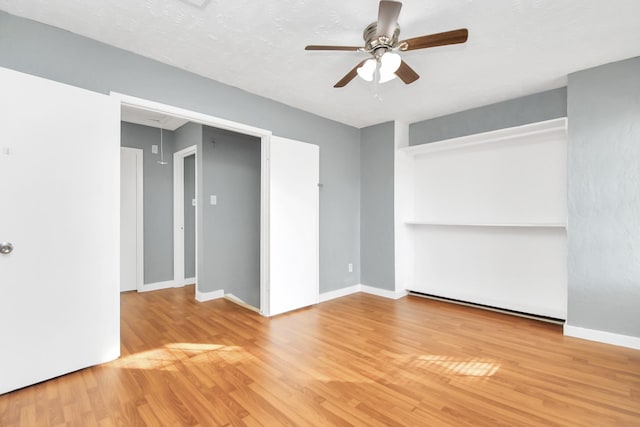 empty room with ceiling fan, light hardwood / wood-style flooring, and a textured ceiling