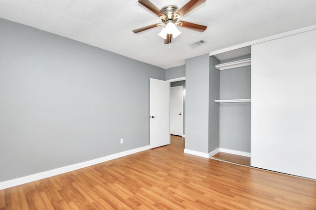 unfurnished bedroom featuring ceiling fan, light wood-type flooring, a textured ceiling, and a closet