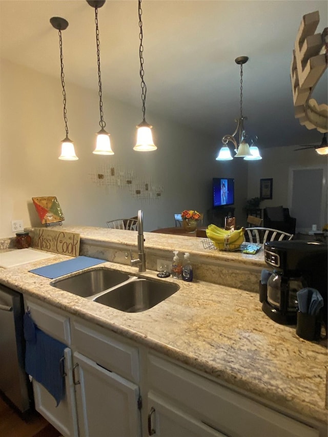 kitchen with decorative light fixtures, dishwasher, sink, white cabinets, and light stone counters