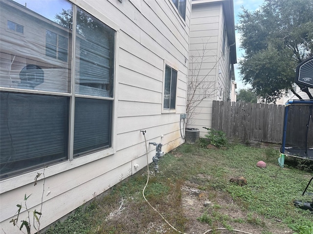 view of side of home with a trampoline and central AC unit