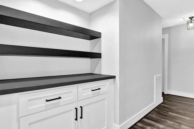 bar with dark hardwood / wood-style floors and white cabinetry