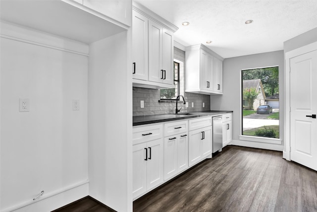 kitchen featuring dishwasher, white cabinets, sink, dark hardwood / wood-style floors, and tasteful backsplash