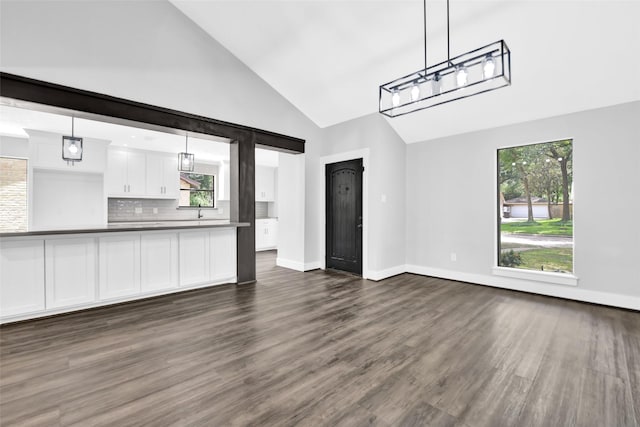 unfurnished living room featuring high vaulted ceiling and dark wood-type flooring