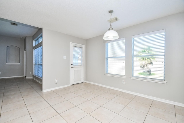 tiled empty room featuring a textured ceiling