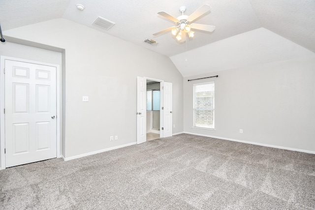 unfurnished bedroom featuring vaulted ceiling, a textured ceiling, ceiling fan, and carpet