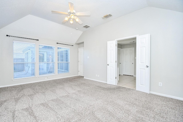 unfurnished bedroom featuring lofted ceiling, light carpet, ceiling fan, and a textured ceiling