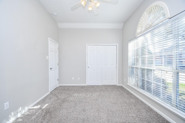 unfurnished bedroom featuring ceiling fan, vaulted ceiling, carpet floors, and a closet