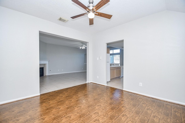 empty room with sink, ceiling fan, light hardwood / wood-style flooring, and a tile fireplace