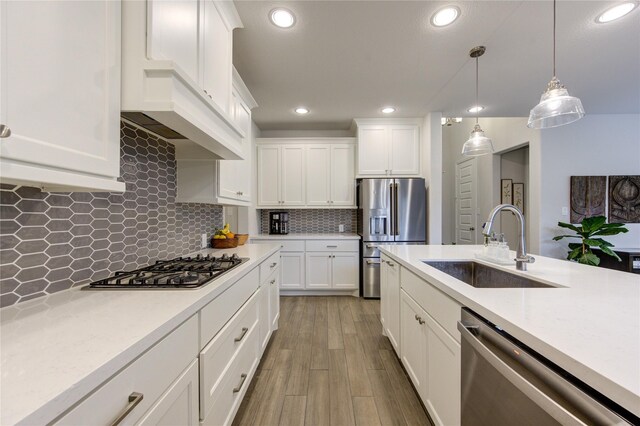 kitchen with sink, stainless steel appliances, tasteful backsplash, decorative light fixtures, and white cabinets