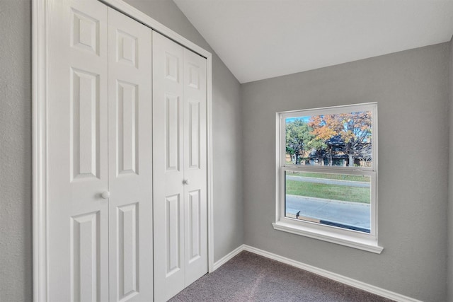 unfurnished bedroom featuring carpet, a closet, lofted ceiling, and multiple windows