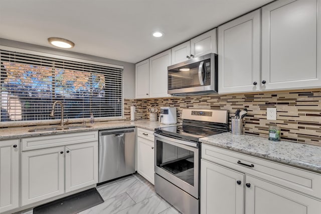 kitchen with backsplash, sink, white cabinets, and stainless steel appliances