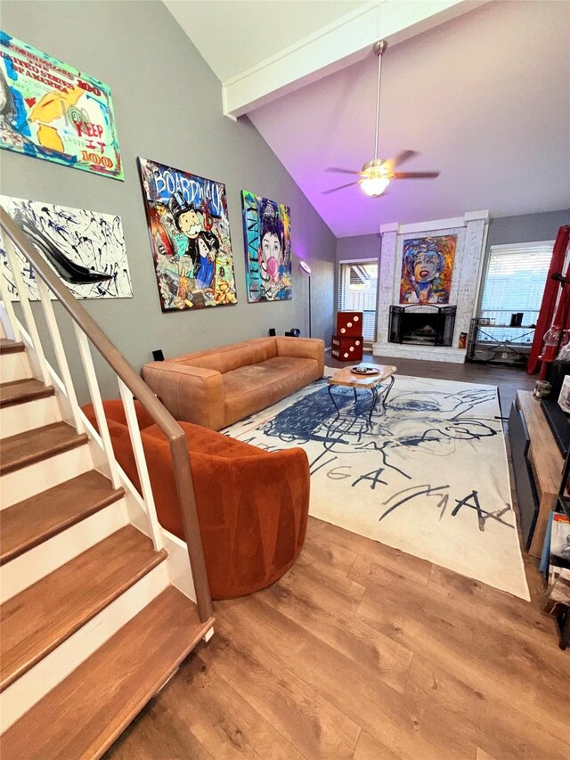 living room with wood-type flooring, ceiling fan, a fireplace, and beam ceiling