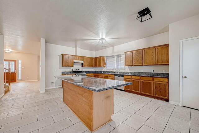 kitchen featuring a textured ceiling, a center island, dark stone countertops, light tile patterned floors, and appliances with stainless steel finishes