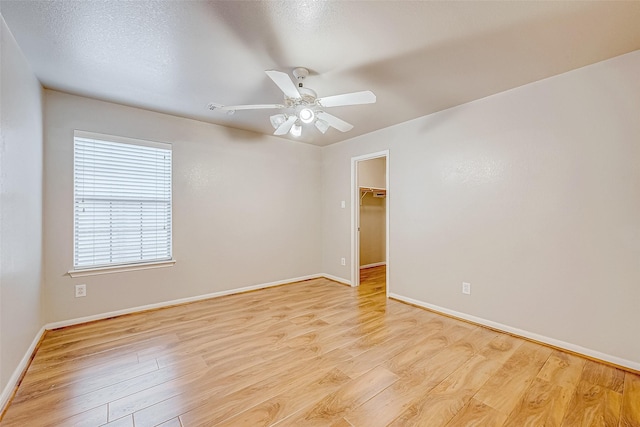 unfurnished room with ceiling fan, a textured ceiling, and light wood-type flooring