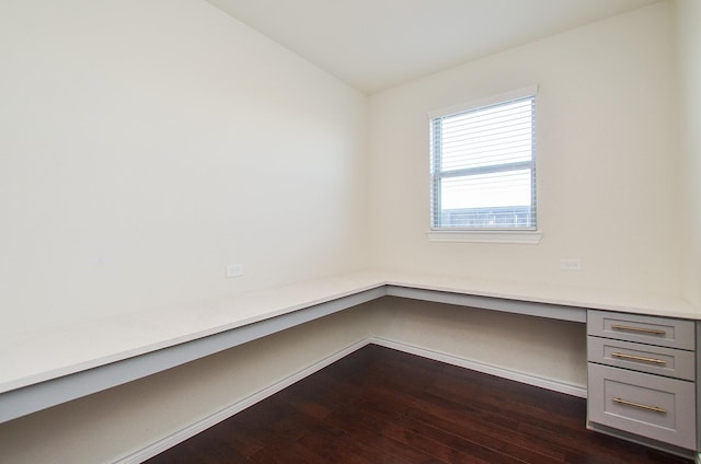 unfurnished office featuring built in desk, dark hardwood / wood-style flooring, and lofted ceiling