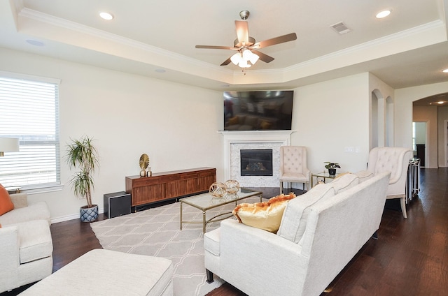 living room featuring dark hardwood / wood-style flooring, a raised ceiling, plenty of natural light, and ornamental molding