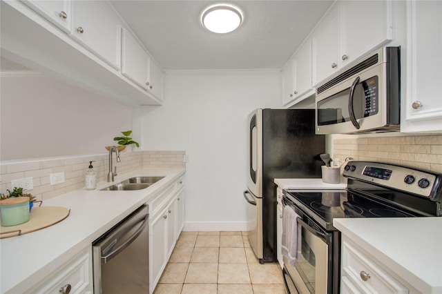 kitchen with appliances with stainless steel finishes, tasteful backsplash, sink, white cabinets, and light tile patterned floors