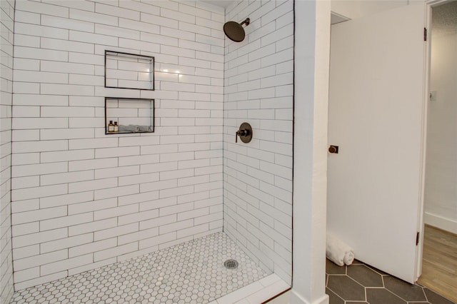 bathroom with tiled shower and tile patterned floors