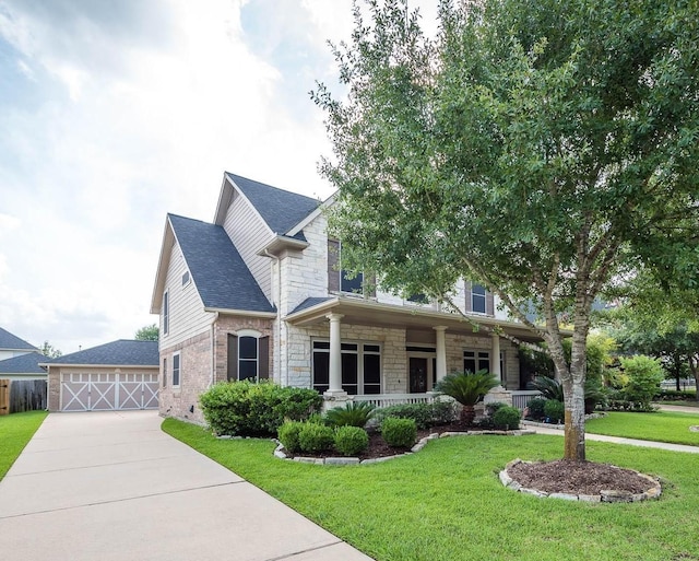 view of front of home with covered porch, a garage, an outdoor structure, and a front yard