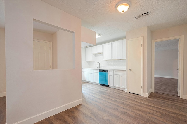 kitchen with sink, light hardwood / wood-style flooring, stainless steel dishwasher, decorative backsplash, and white cabinets