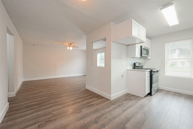 kitchen with white cabinets, stainless steel appliances, tasteful backsplash, and dark hardwood / wood-style floors