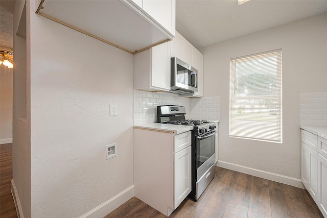 kitchen with decorative backsplash, dark hardwood / wood-style flooring, stainless steel appliances, and white cabinets