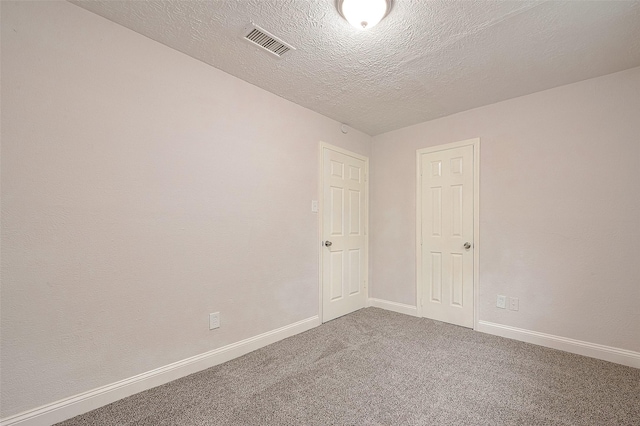 carpeted empty room featuring a textured ceiling