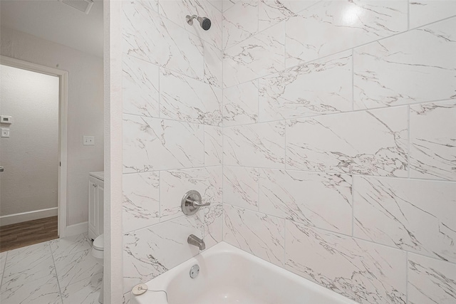 bathroom featuring tiled shower / bath combo and toilet