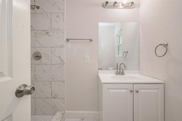 bathroom featuring a tile shower and vanity