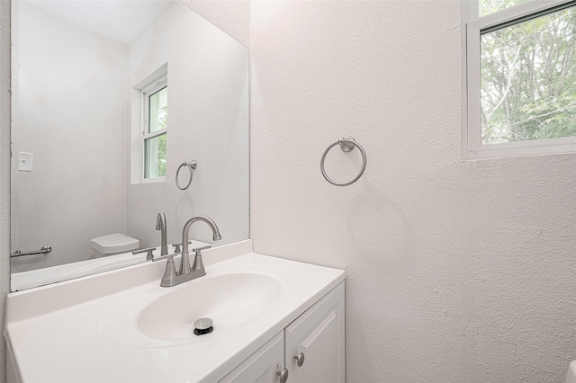 bathroom with vanity, toilet, and plenty of natural light