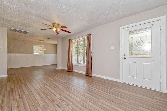 foyer entrance featuring ceiling fan with notable chandelier, light wood-type flooring, and a textured ceiling