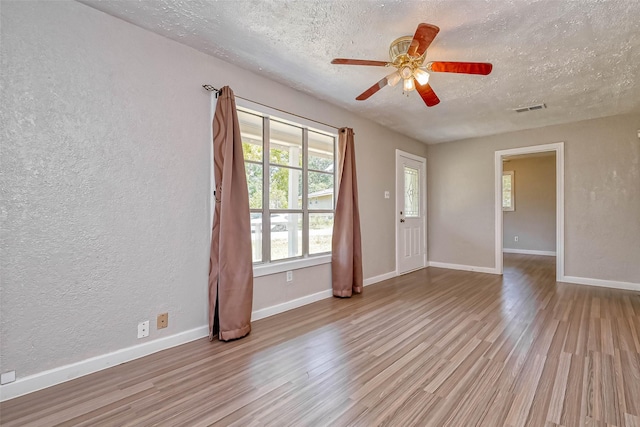 empty room with light wood-type flooring, a textured ceiling, and ceiling fan