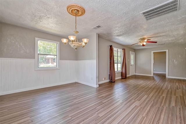 spare room featuring ceiling fan with notable chandelier, hardwood / wood-style flooring, and plenty of natural light