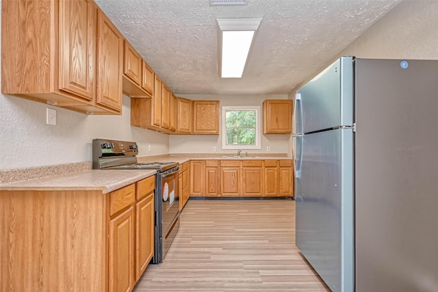 kitchen featuring sink, light hardwood / wood-style flooring, stainless steel fridge, a textured ceiling, and black / electric stove