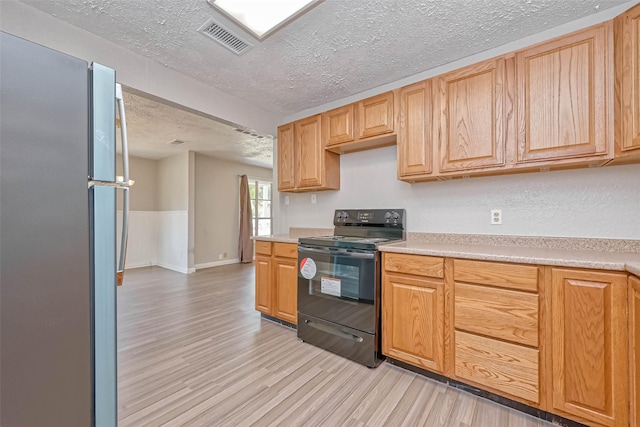 kitchen featuring light hardwood / wood-style floors, a textured ceiling, stainless steel refrigerator, and black electric range