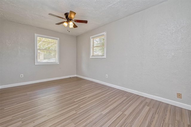 spare room featuring a wealth of natural light, light hardwood / wood-style flooring, ceiling fan, and a textured ceiling