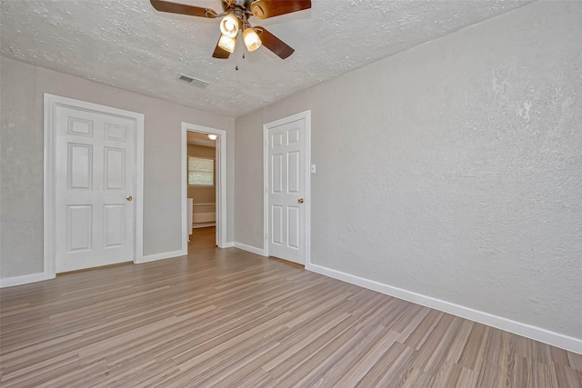 empty room featuring a textured ceiling, light hardwood / wood-style flooring, and ceiling fan