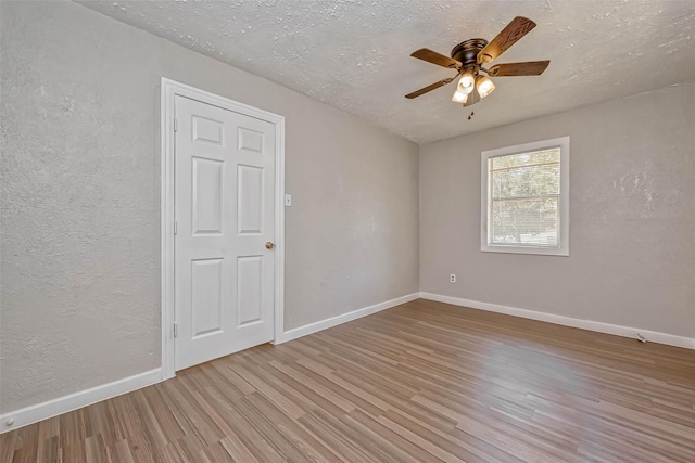 unfurnished room featuring ceiling fan, light wood-type flooring, and a textured ceiling