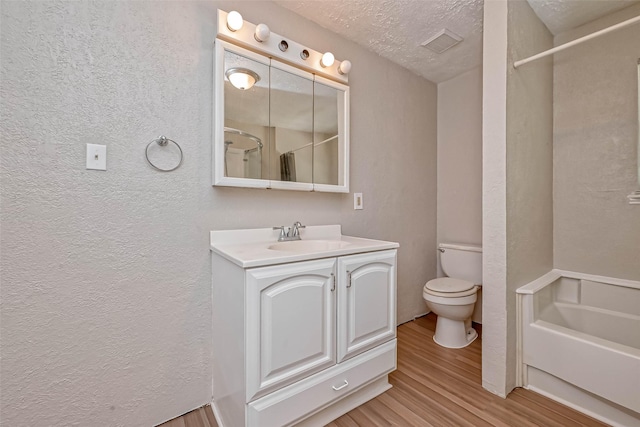 bathroom with walk in shower, a textured ceiling, toilet, vanity, and hardwood / wood-style flooring