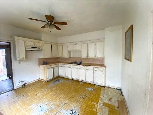 kitchen with white cabinets, backsplash, ceiling fan, and sink