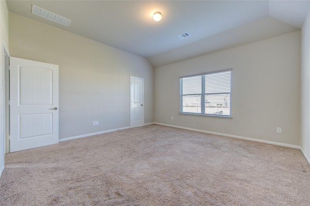 spare room with light carpet and vaulted ceiling