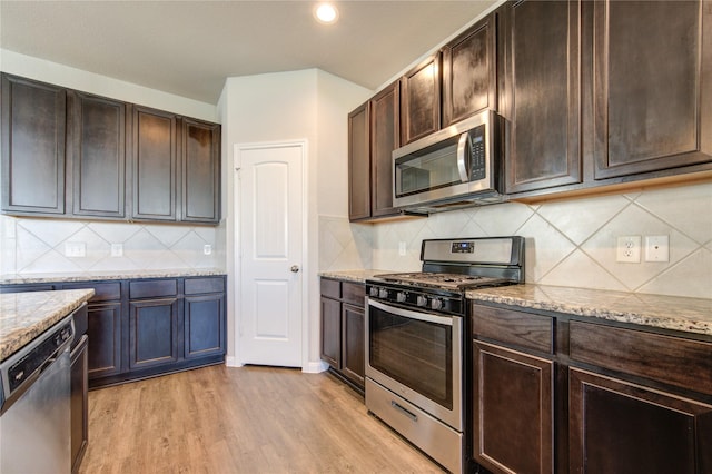 kitchen featuring appliances with stainless steel finishes, dark brown cabinetry, light hardwood / wood-style floors, and light stone counters