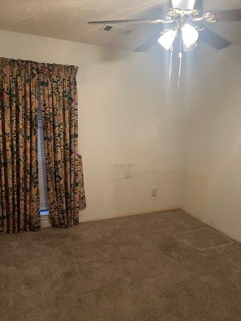 carpeted empty room with ceiling fan and a textured ceiling